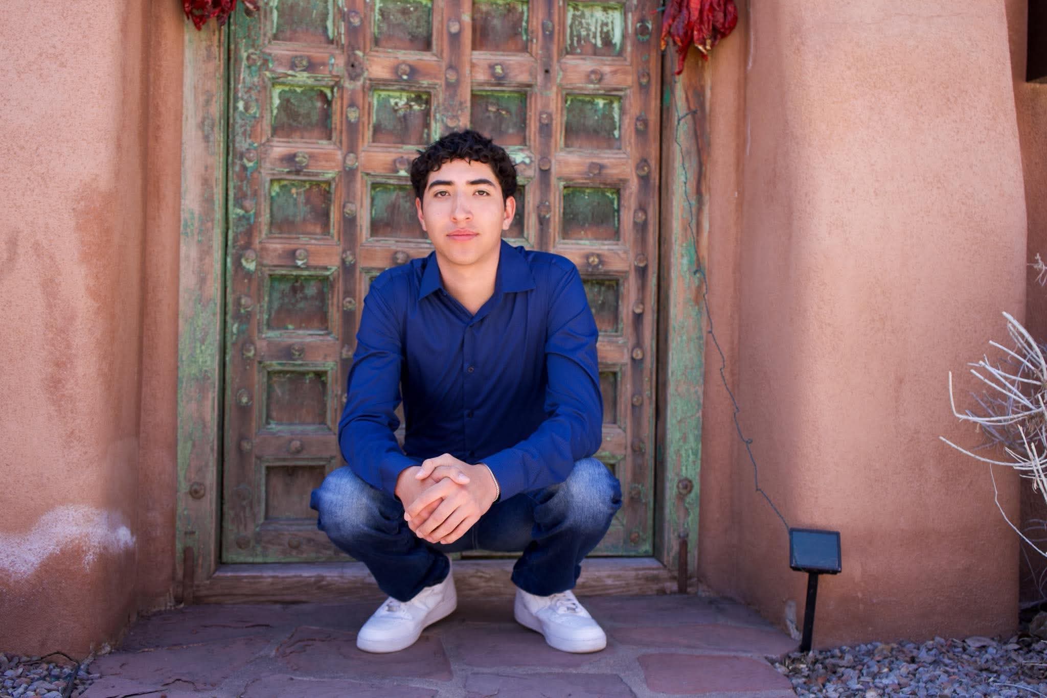 Senior portrait at an adobe doorway with chile ristras