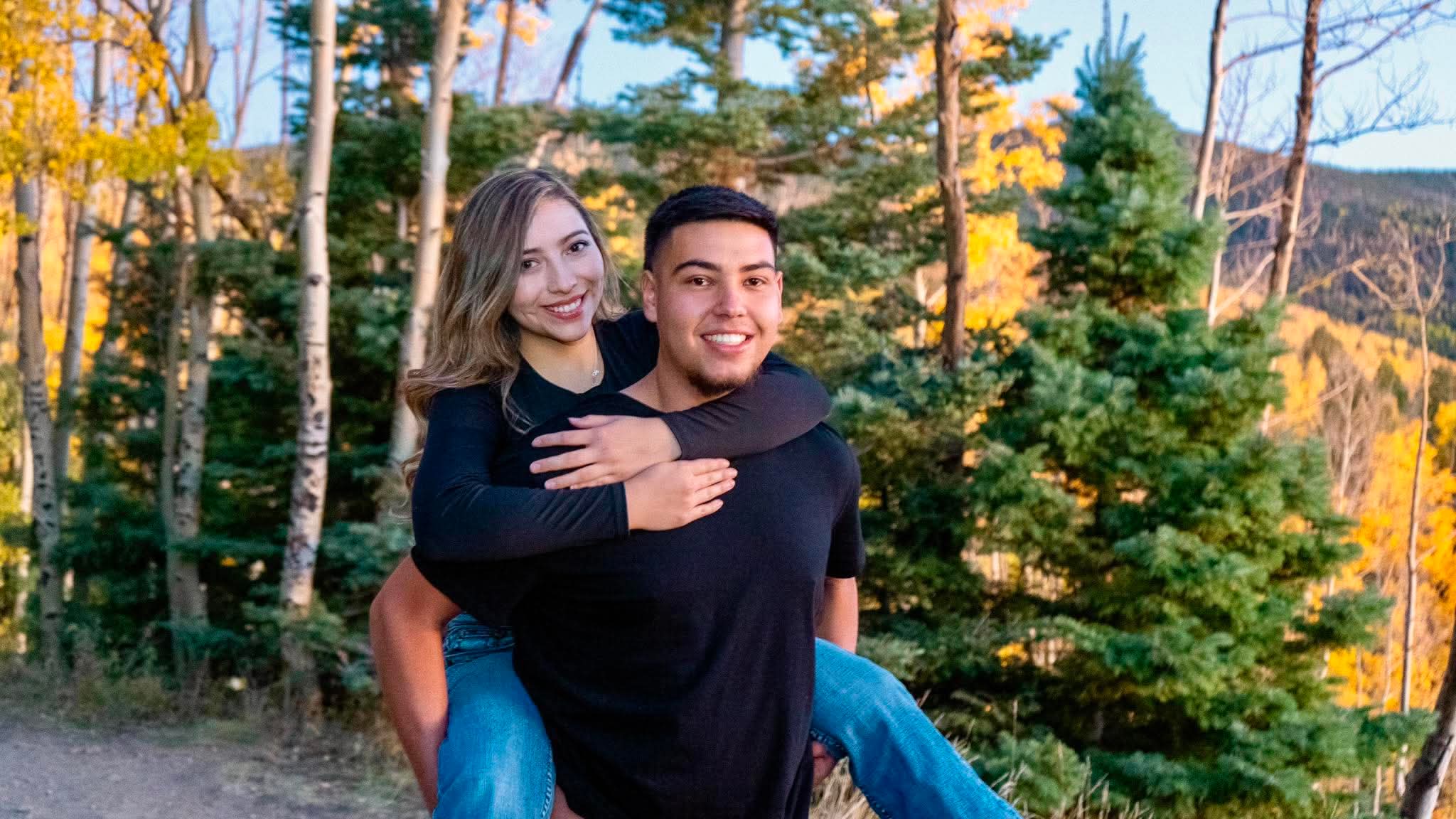 A couple laughing, piggyback, autumn forest