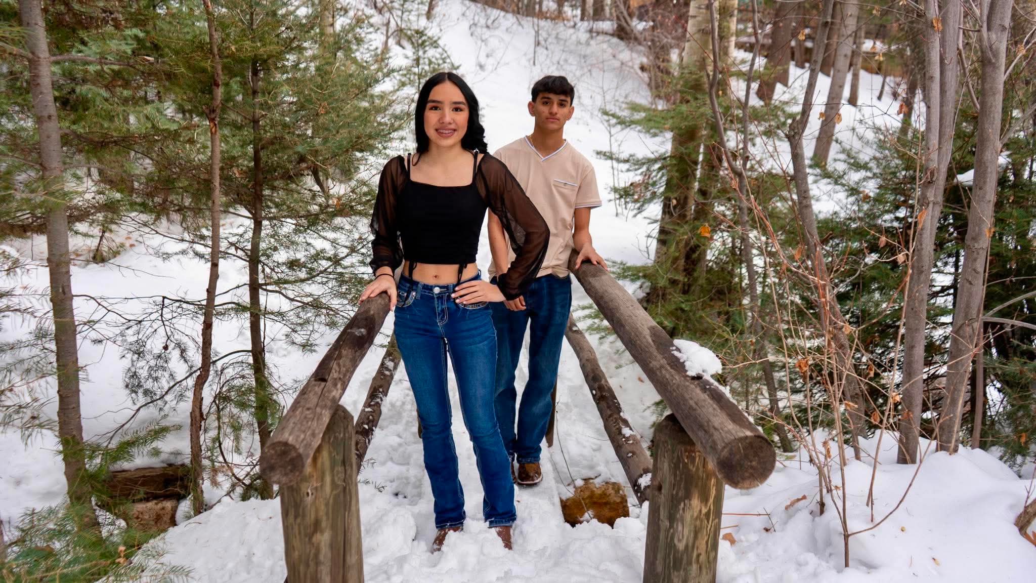 Two siblings on a snowy wooden bridge