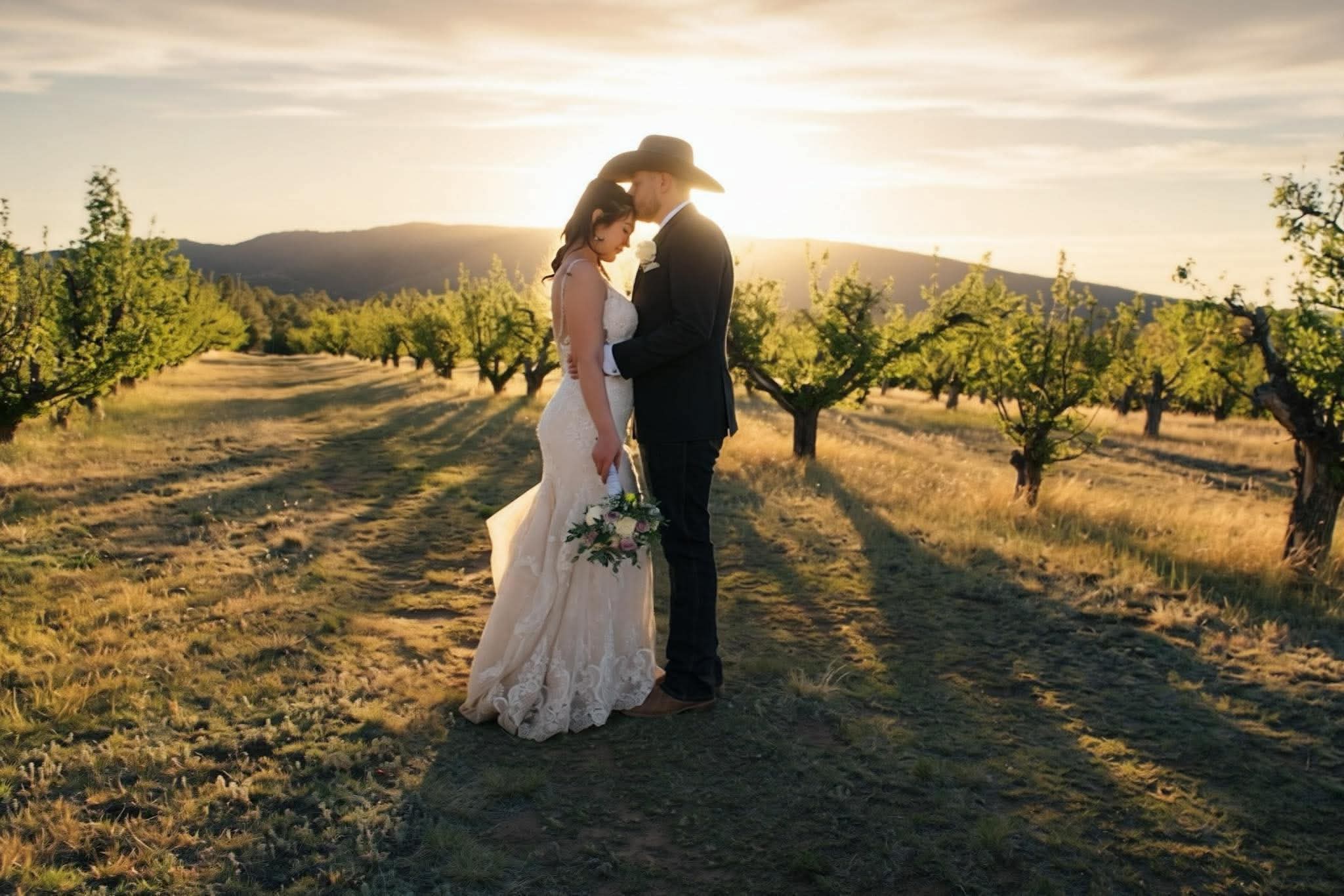 Bride and groom embracing in an orchard at sunset